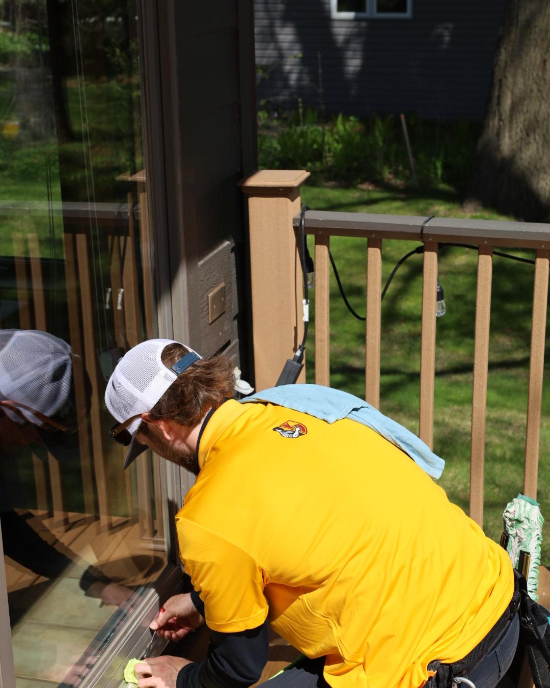 A Strongman technician kneeling to hand-detail a sliding door track