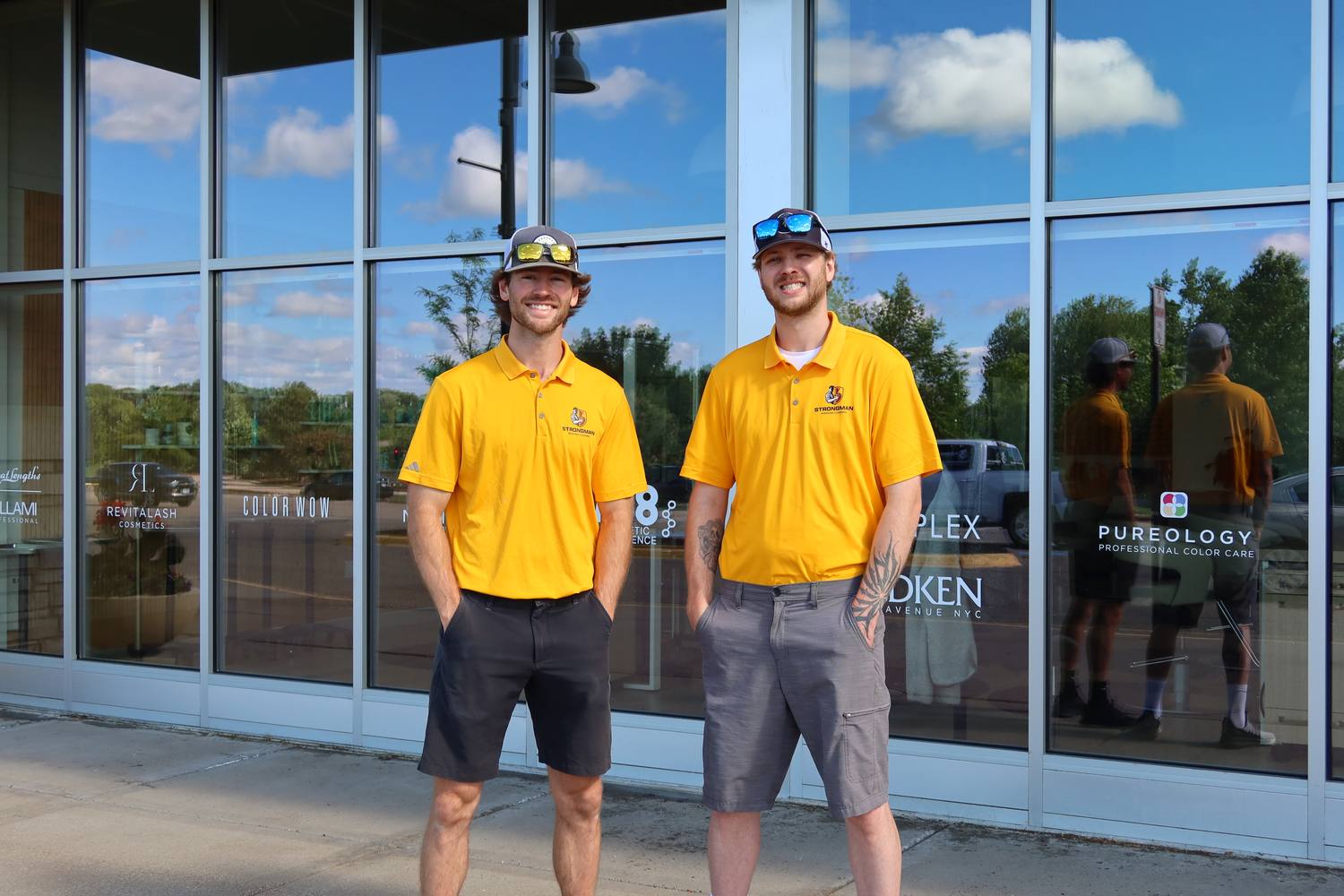 The Strongman Window Cleaning team in uniform in front of freshly cleaned storefront glass